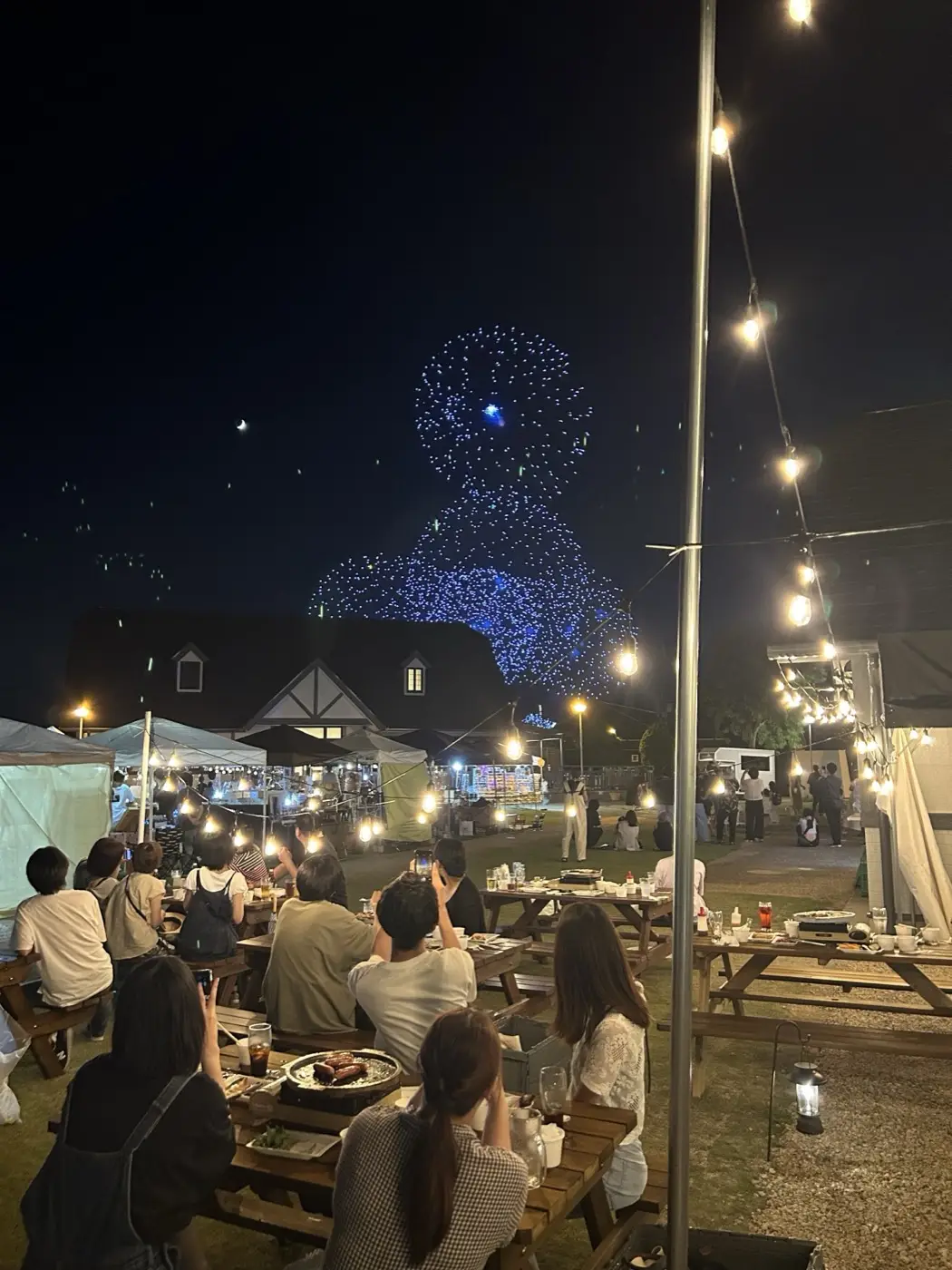 夜空のドローンショーとビアガーデンのお客さん